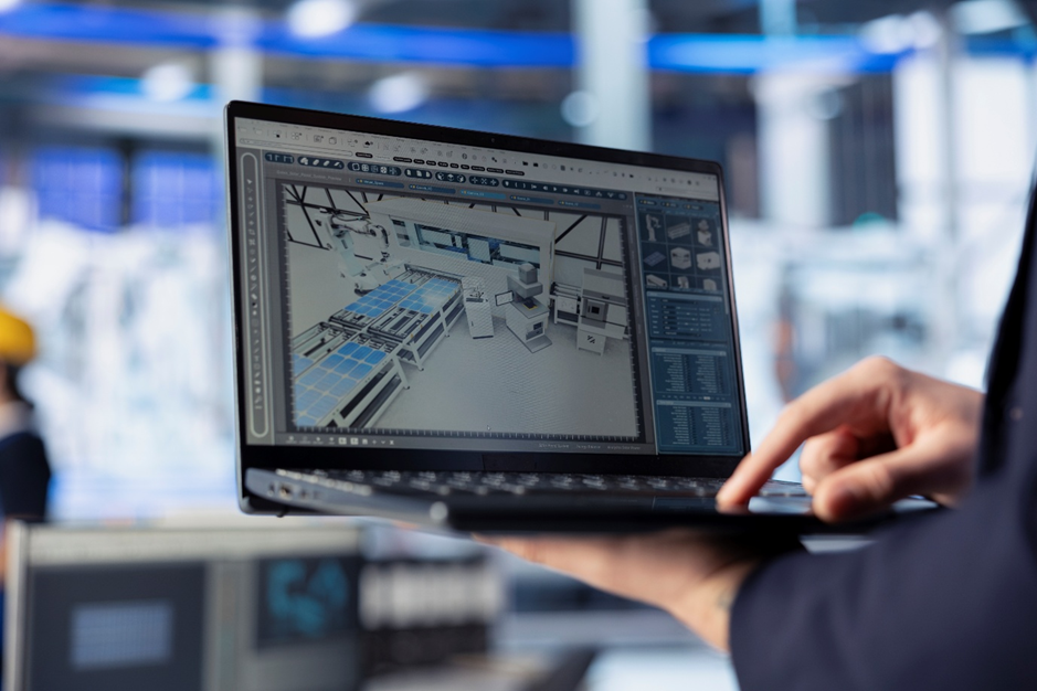 Worker analyzing solar panel production line through BIM simulation on a laptop screen