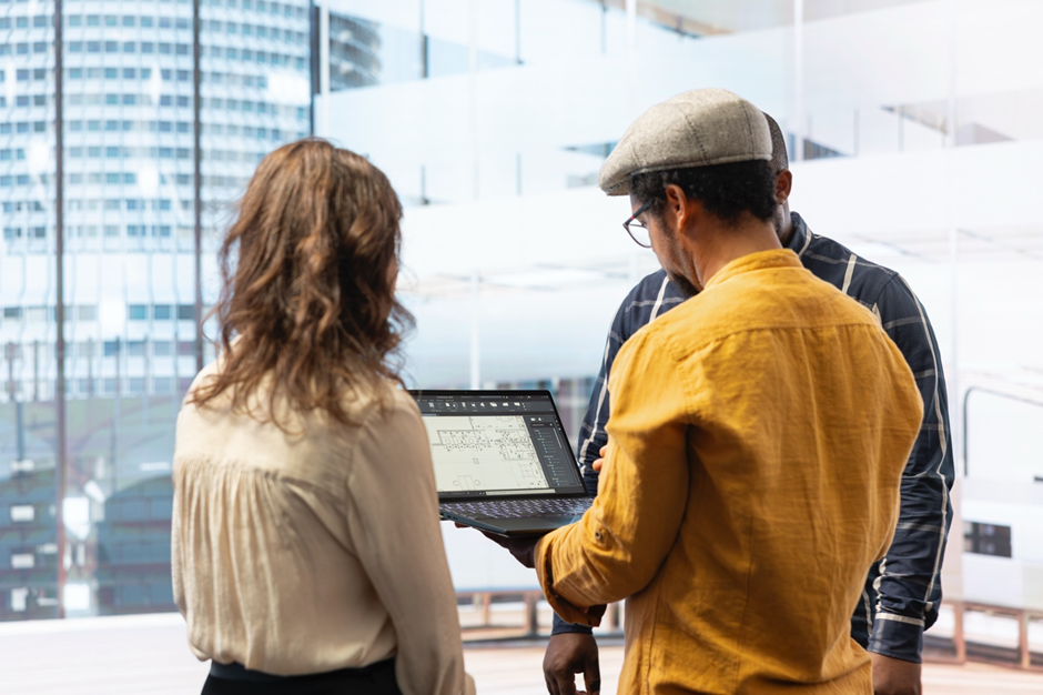 Architects collaborating while reviewing a digital building floor plan on a laptop
