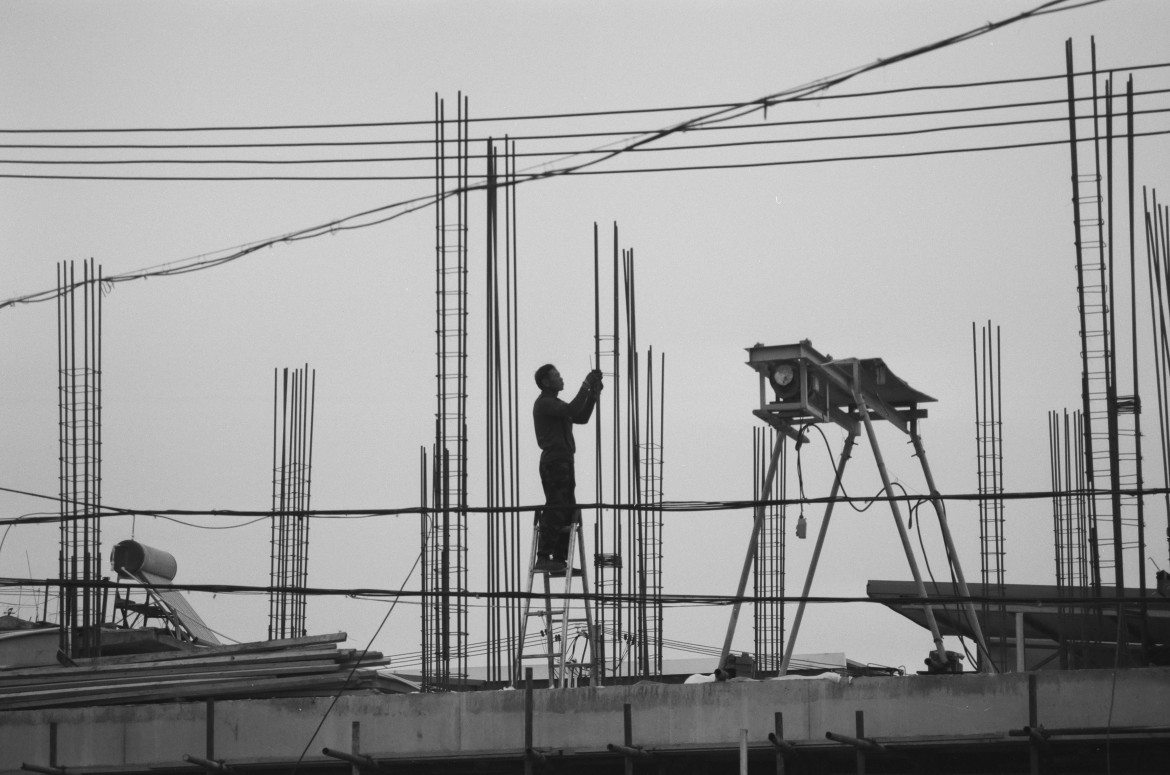 Construction worker installing steel reinforcement bars on a building site.